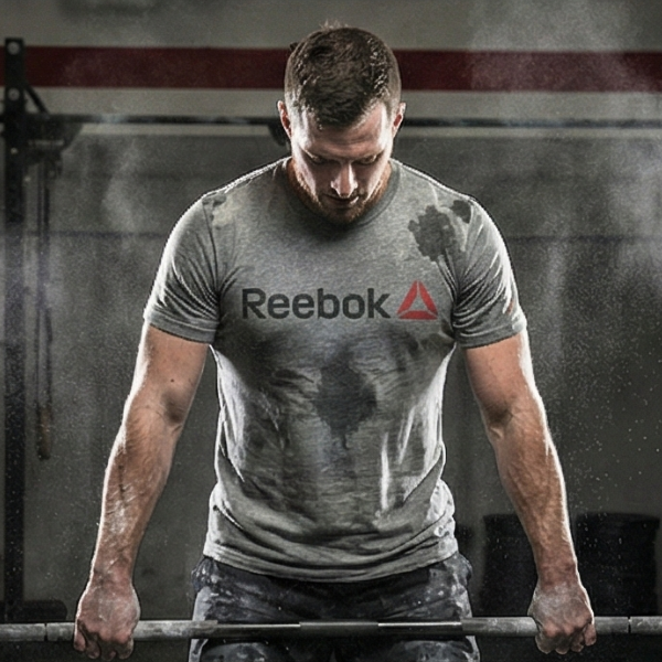 Atleta de CrossFit levantando barra cargada usando camiseta gris Reebok resistente a la abrasión y el sudor.