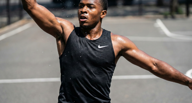 Atleta entrenando al aire libre con camiseta deportiva negra sin mangas para máxima libertad de movimiento.